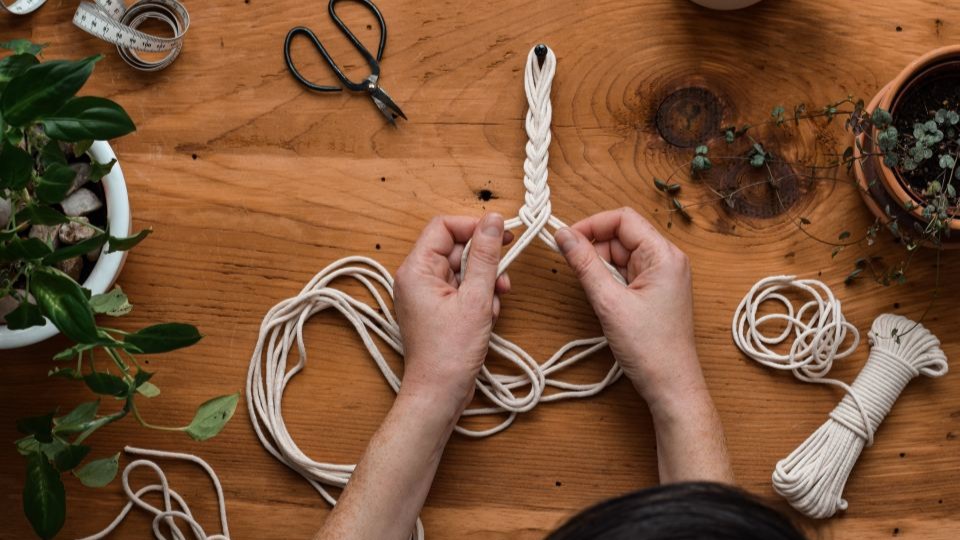 A macrame plant hanger being made.