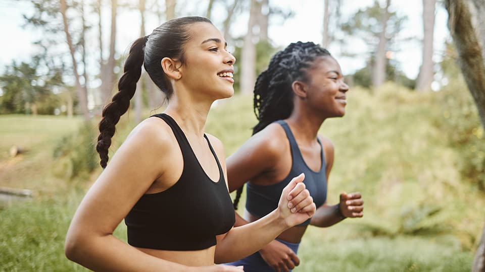 Two women running on a woodland trail