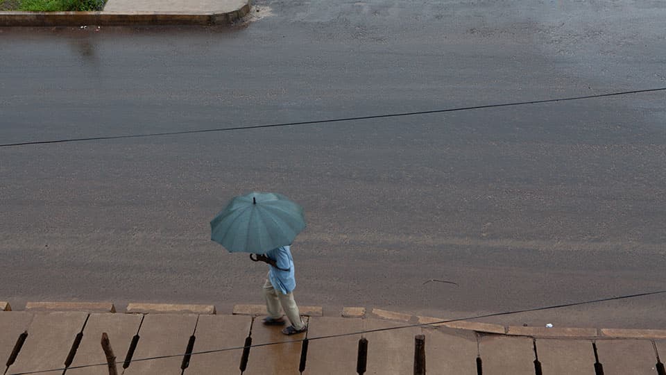 Man walks through flooded street with an umbrella
