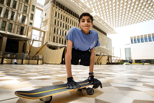 Current student Ghanim smiling at the camera on a skateboard