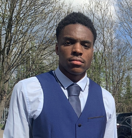 Headshot of current Master's student Philip stood outside wearing a shirt, tie and blue waistcoat