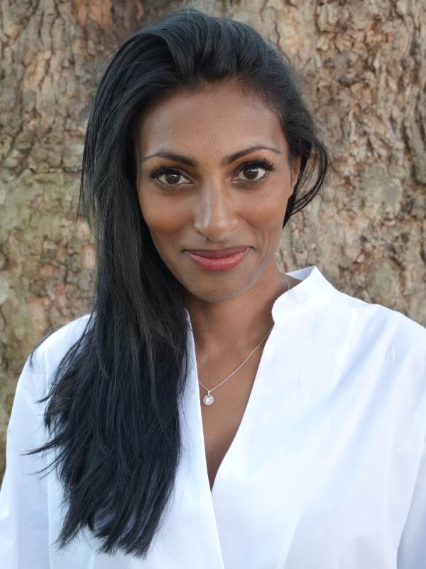 Headshot of Dr Shini wearing a white shirt and smiling towards the camera