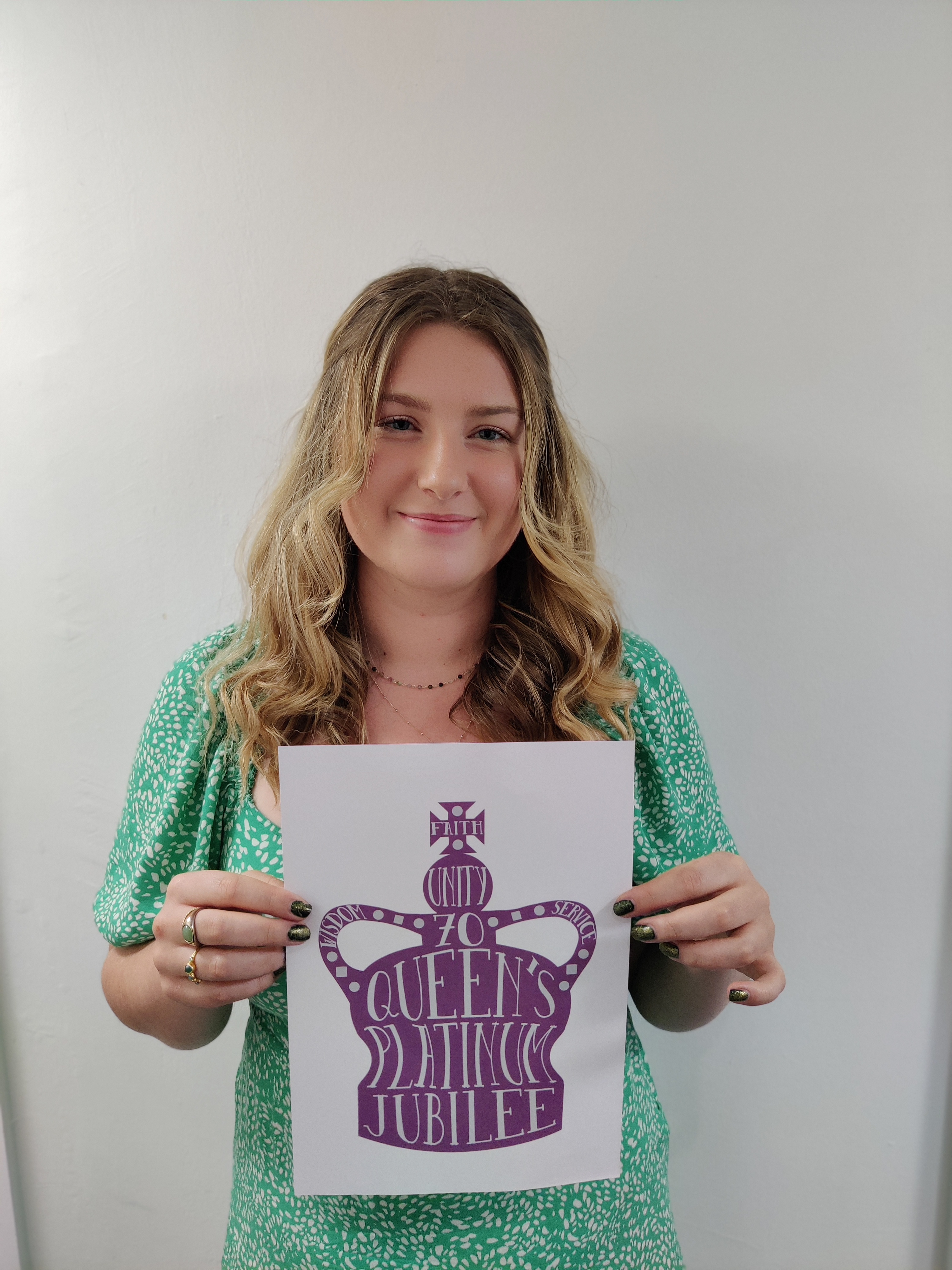 Student Hannah Lynes holding paper with her purple crown design on