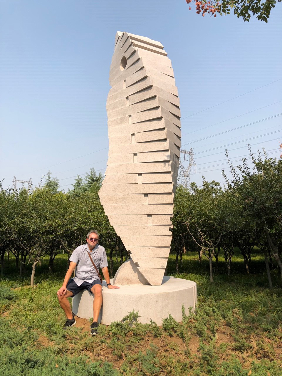 photo of John sat by his 2019 sculpture, Twister