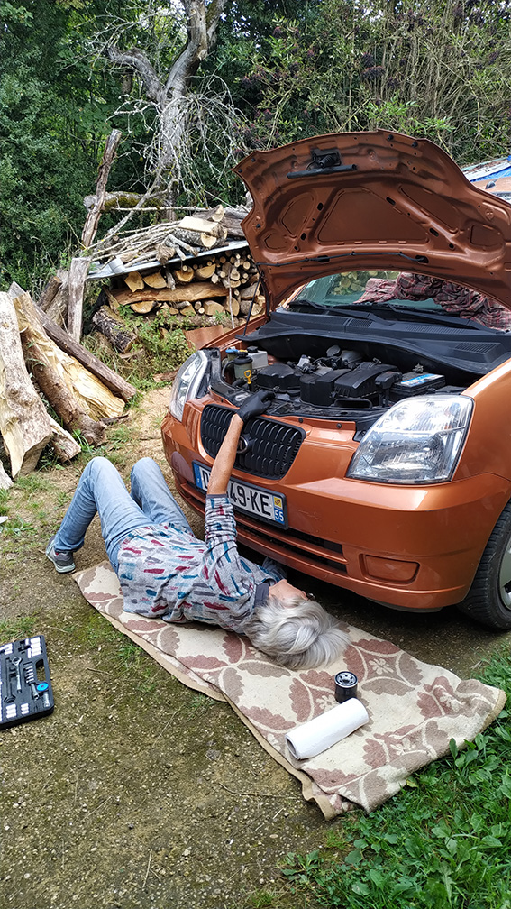 A woman changing the oil filter on her car.