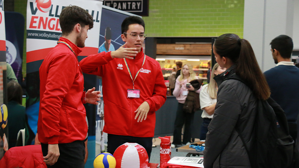 A student speaking to two representatives from Volleyball England