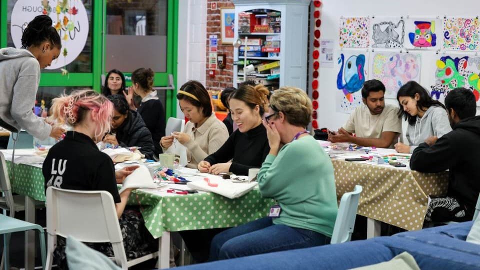 A group of people sat around tables creating art at an LU Arts workshop.