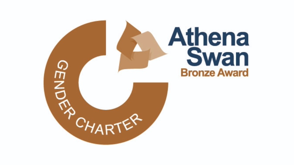A bronze ring with a quarter chunk removed. In its place is a bronze triangle made of scrolls. Text reads: 'Gender Charter: Athena Swan Bronze Award'