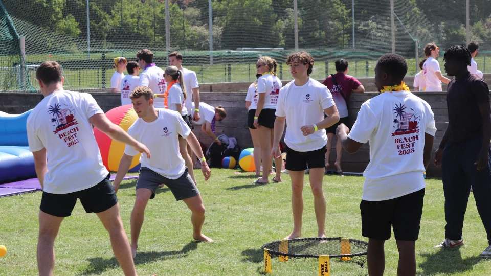 Students playing a game outdoors wearing 'Beach Fest 2023' t-shirts.