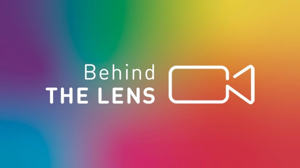 Rainbow background with words 'Behind The Lens'