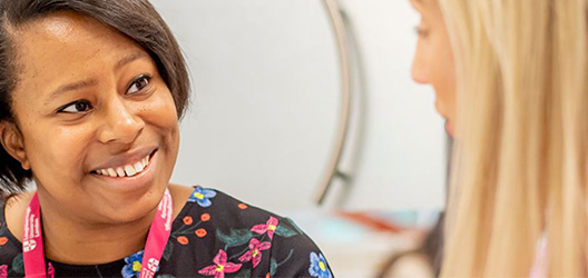 Close-up photo of two staff members talking to each other and smiling