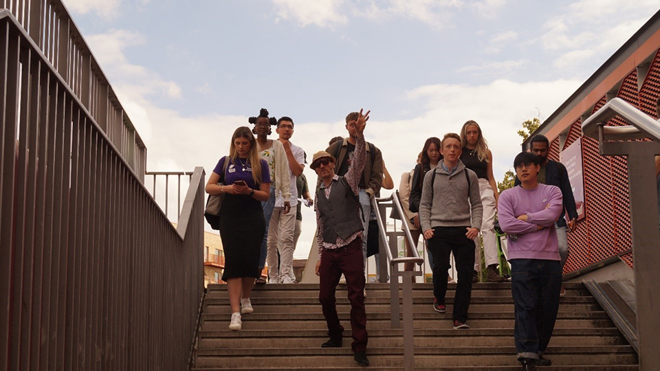 Photo of a group of student attendees walking down a flight of stairs outside as part of their walking tour