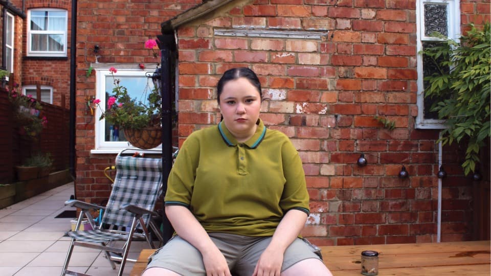 Charlotte sat outside her house on a bench in a green polo