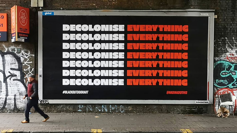 Billboard that says Decolonise Everything repeated over and over in white and red text