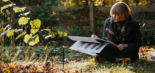 photo of alumna Emma Britton outside with sketches 