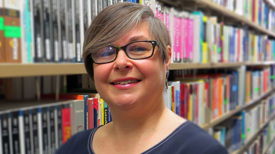 Emma Walton in front of stack of books 