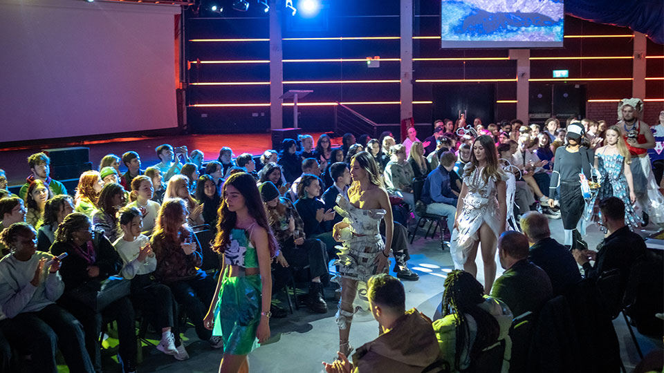 models walk on catwalk in between a big audience