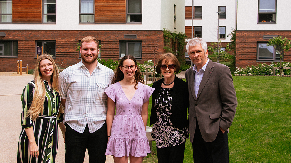 Photo of the team who design Flux stood next to Barry and Valerie Eccleston, in front of the space where the sculpture will reside by the Claudia Parsons hall of residence