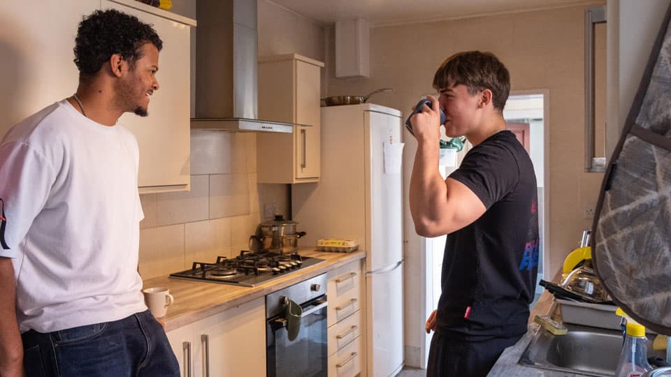 Two students chatting in the kitchen of their shared off campus accomodation