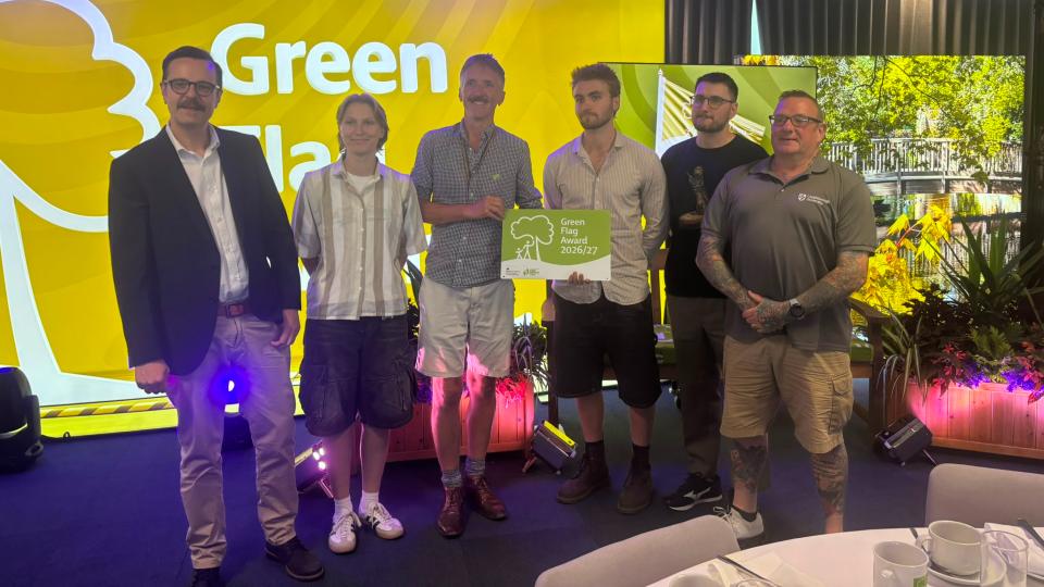 Six people standing together, one is holding a Green Flag Award certificate.