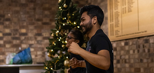 photo of a student dancing in a dining room with Christmas tree in background