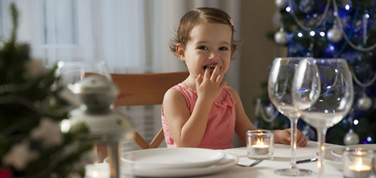 A child eating at a table with a festive back drop.

