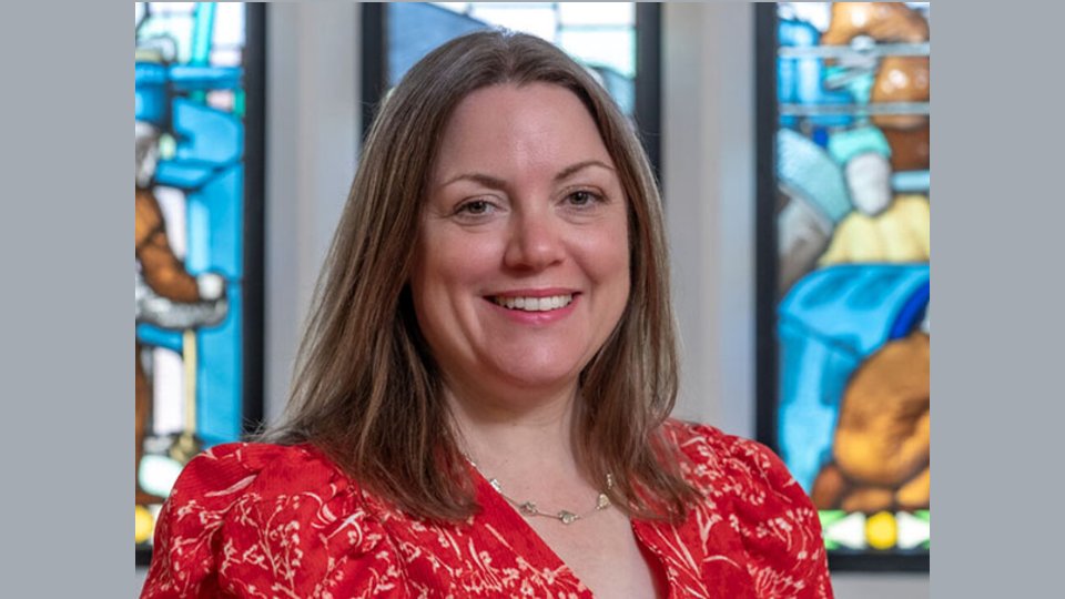 Close-up of Dr Kathryn North in front of stained glass windows.