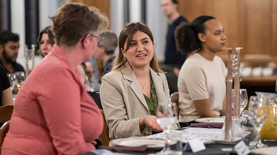 Photo of a staff member and a student talking to each other sat by a table