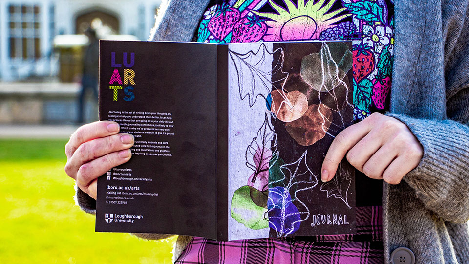 Someone holding a journal so you can see the colourful cover
