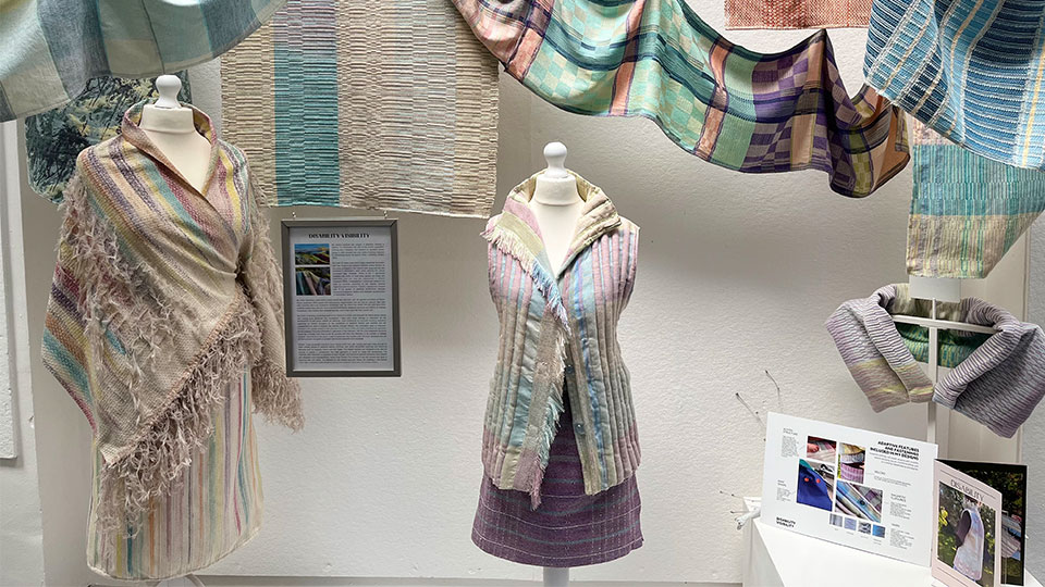 Colourful woven clothing designs displayed on mannequins and hanging behind mannequins