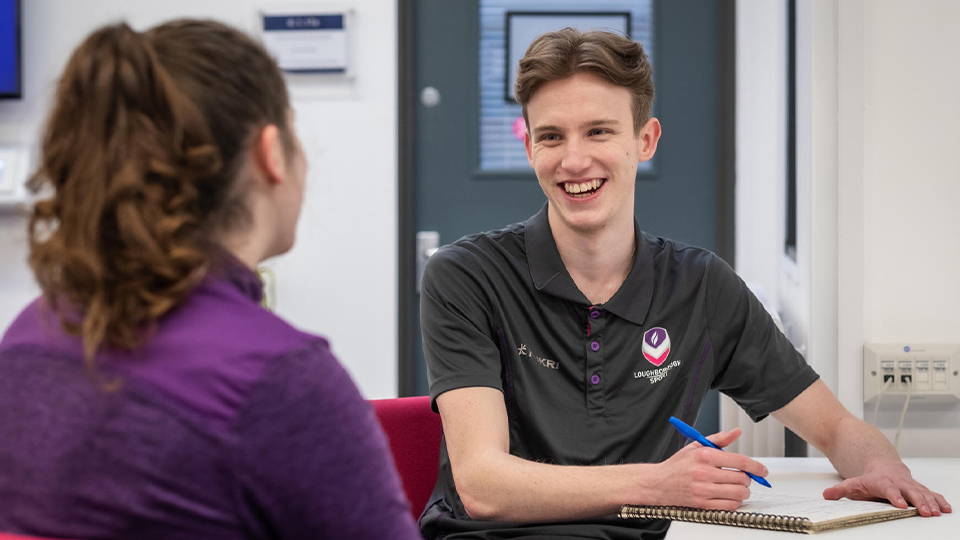 Loughborough Sport staff sitting together having a conversation at a desk