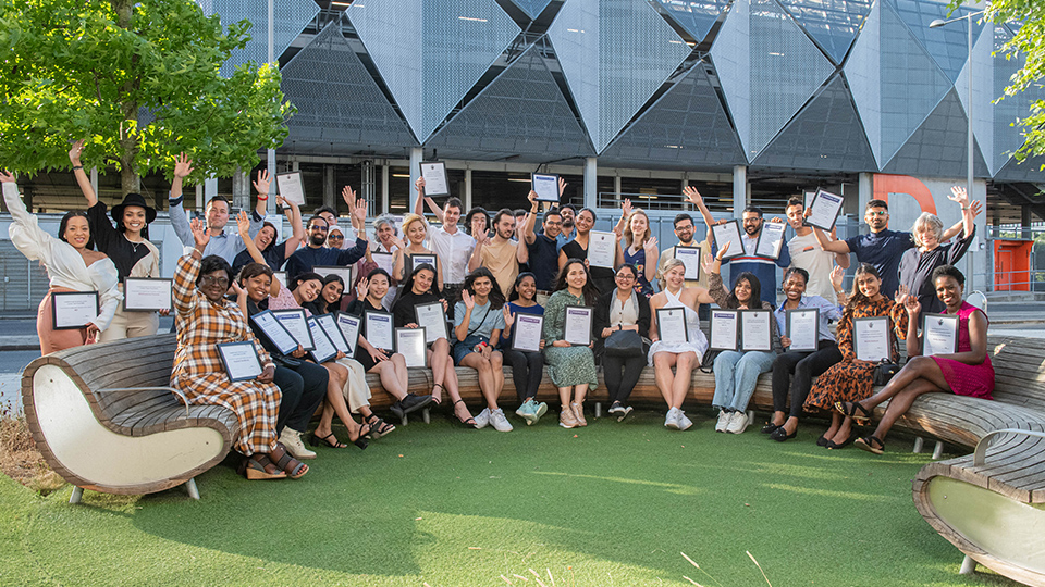 Photos of students, scholars and members of the community sat together outside holding framed certificates and smiling at the camera