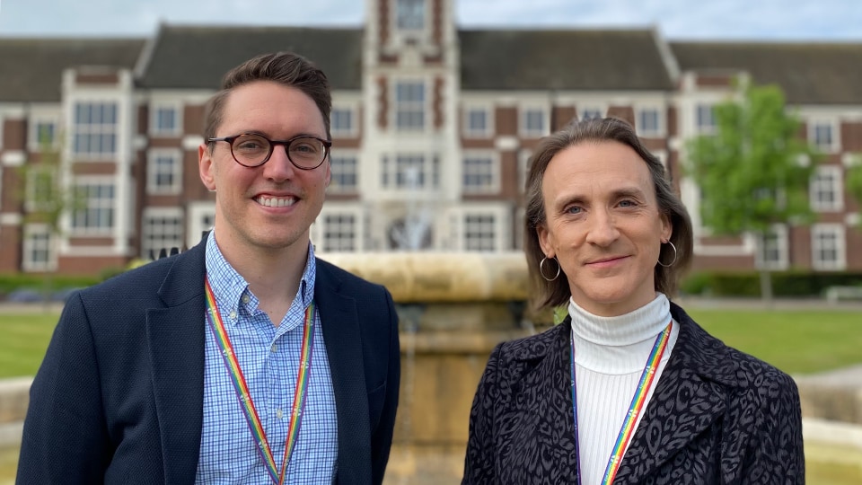 Photo of Dr Chris McLeod and Stevie Ashurst stood smiling at the camera in front of the Hazlerigg Building and Fountain