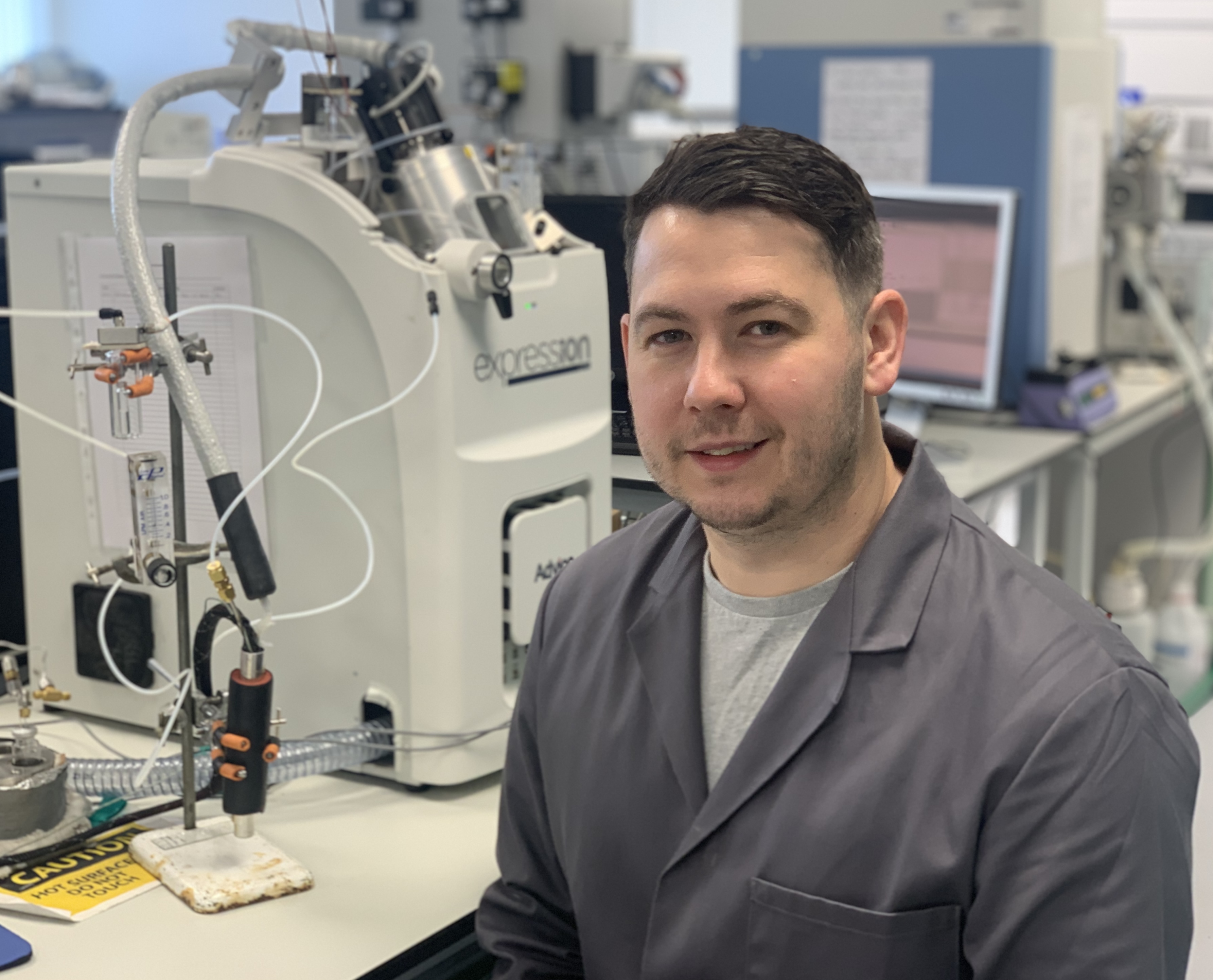 Headshot of Liam Heaney in a lab jacket in one of the University's labs