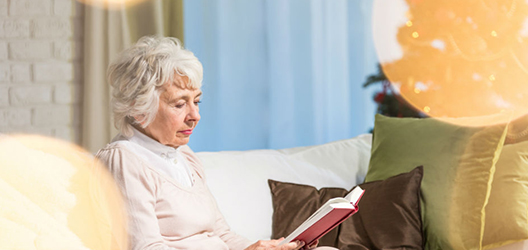 photo of an elderly woman reading a book on a sofa