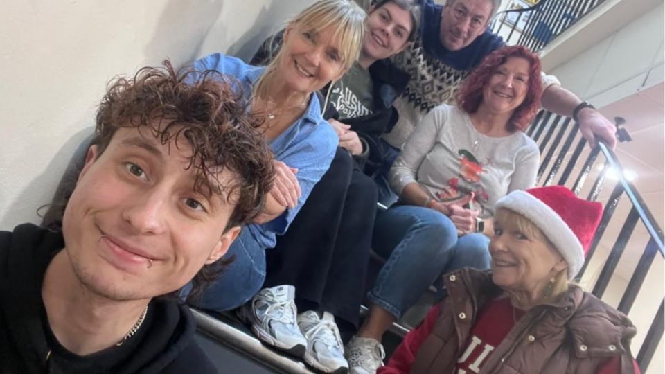 Six people sat on a staircase and smiling at the camera.