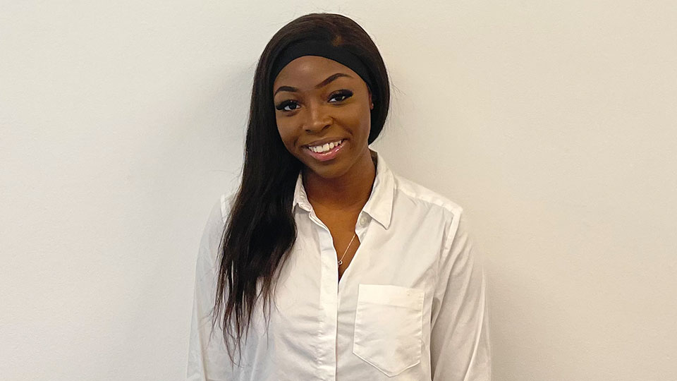 Mary-Anne wearing a white shirt, standing in front of a white wall