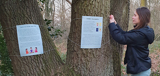 A photo of a student looking at the written activities on a tree trunk as part of a mindfulness walk in Burleigh Woods created by PhD students