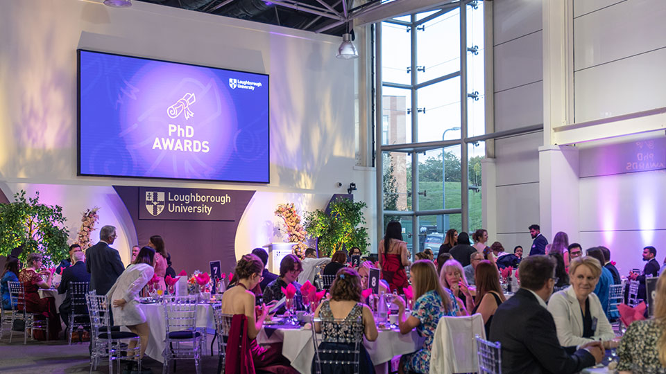 PhD Awards 2026 attendees sat at tables in front of a main stage with a purple screen