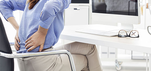 photo of a woman at work experiencing back pain 