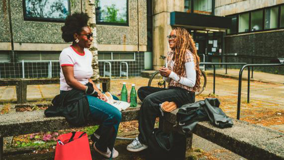 Two students sat chatting on a public bench