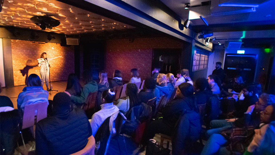 Photo of a performer on the stage in Cognitos, with a seated audience watching