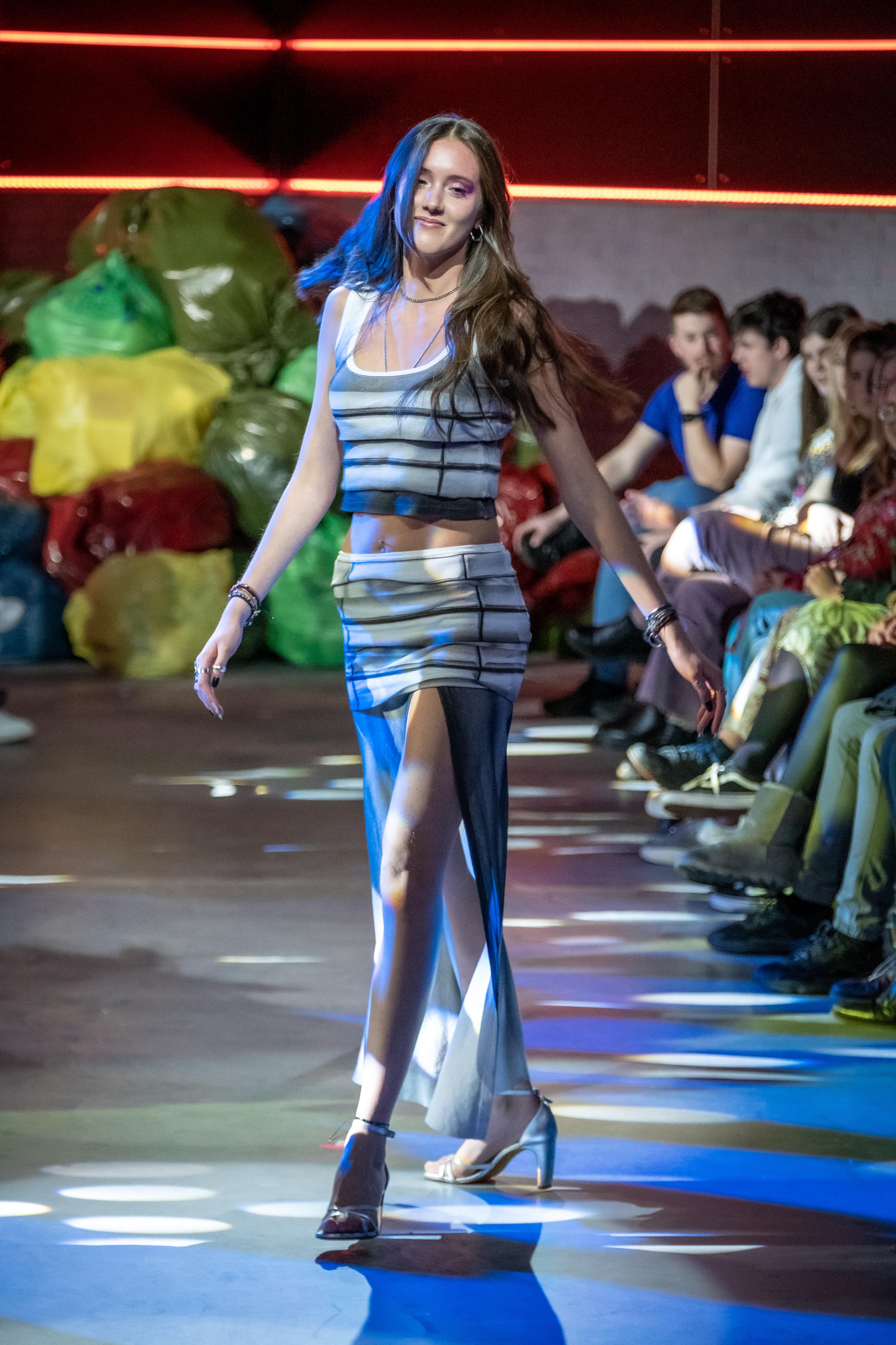 Model wears grey and white striped outfit on the runway