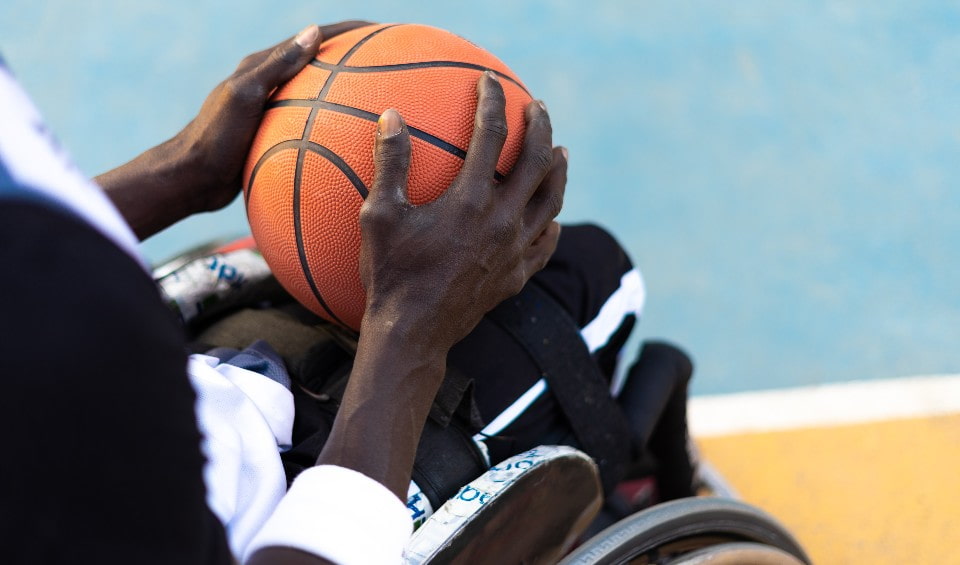 Person in a wheelchair holding a basketball in their hands.