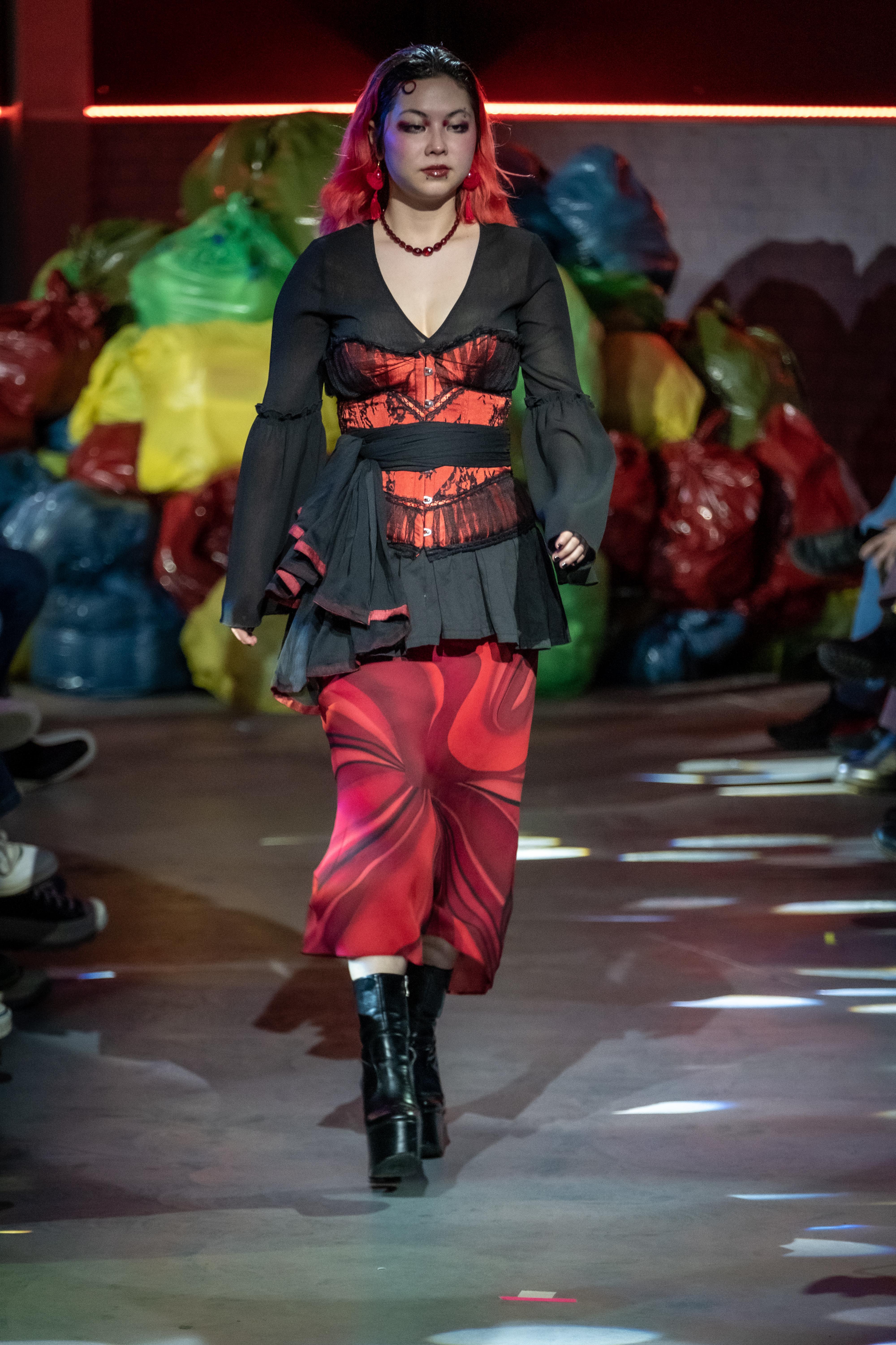 A model walks the runway in a black and red outfit