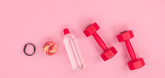Pictured are workout weights, a bottle of water and a peach. 