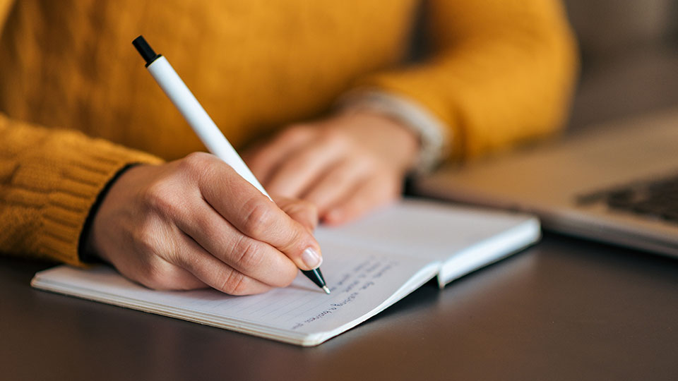 Photo of woman writing in a notebook