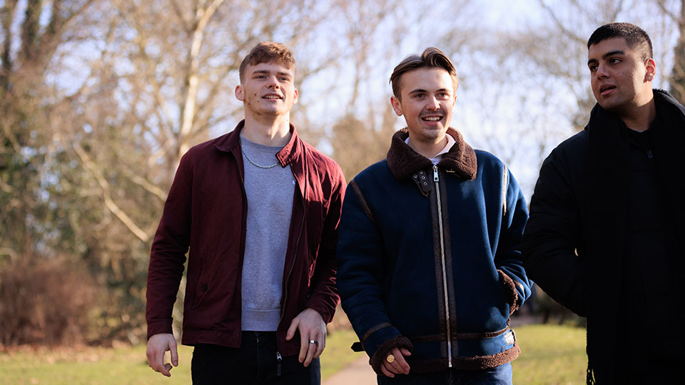 Photo of a group of three young men walking together in a park 